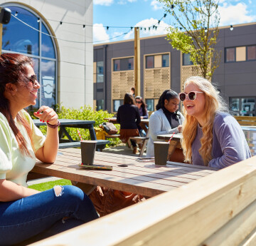 two students sitting outside chatting 