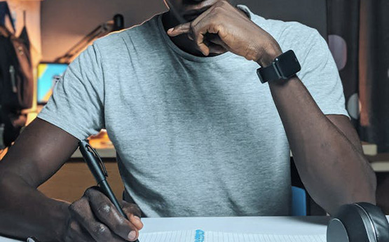 Myfyriwr yn meddwl am yr hyn y byddan nhw'n ei ysgrifennu