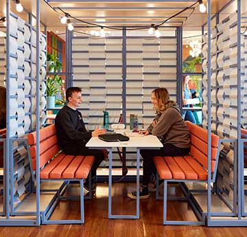 Two students chatting in a booth within Harbwr Fulton on Singleton Campus