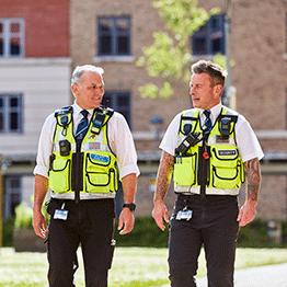 Two male Security and Campus Response team members walking together on Bay Campus on a sunny day. They are smiling and enjoying the weather. 
