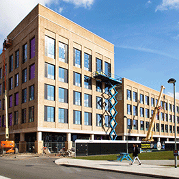 An image showing the Computational Foundry Building on Bay Campus being built. There are cranes and cherry pickers on site and the sky is blue.