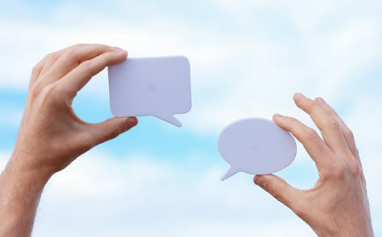 two hands holding cut outs of speech bubbles