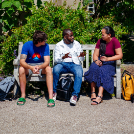 Students on a bench socialising in front of the Abbey on Singleton Campus
